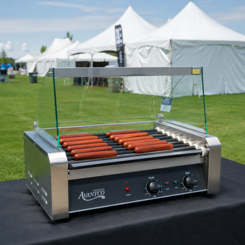 Stainless steel hot dog roller grill with sneeze guard at an outdoor event
